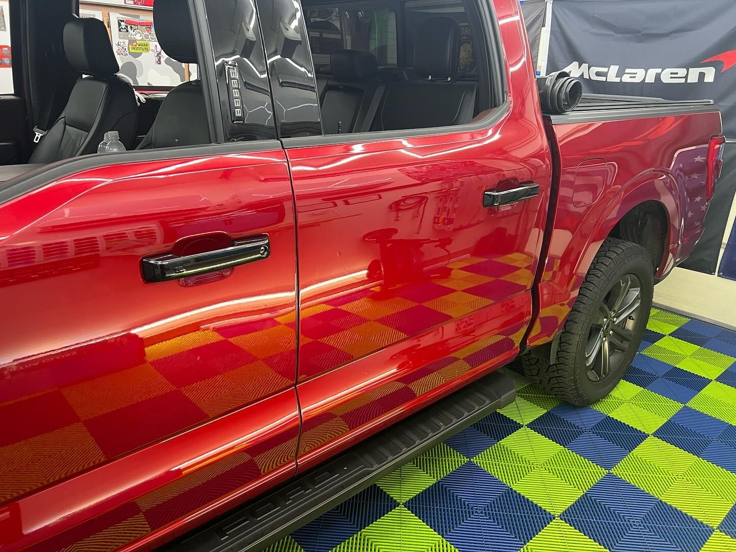 Red pickup truck with black accents, parked on checkered floor.