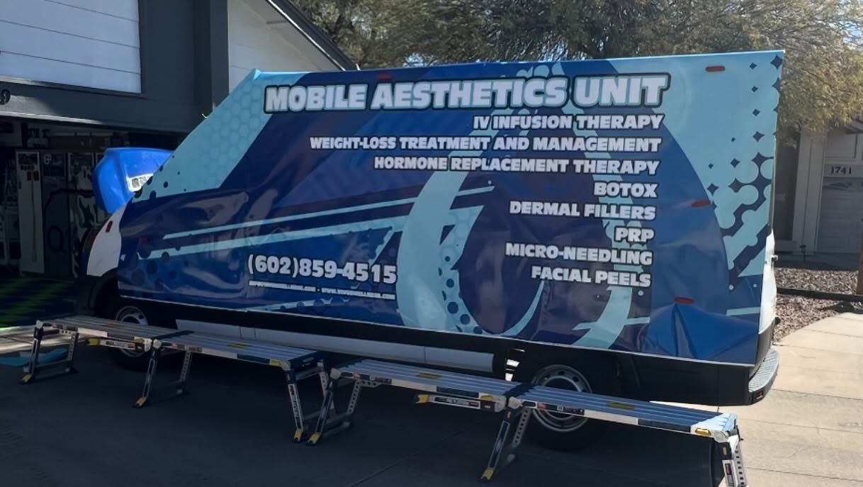 Mobile aesthetics unit van offering services like Botox and dermal fillers; parked outside with benches.