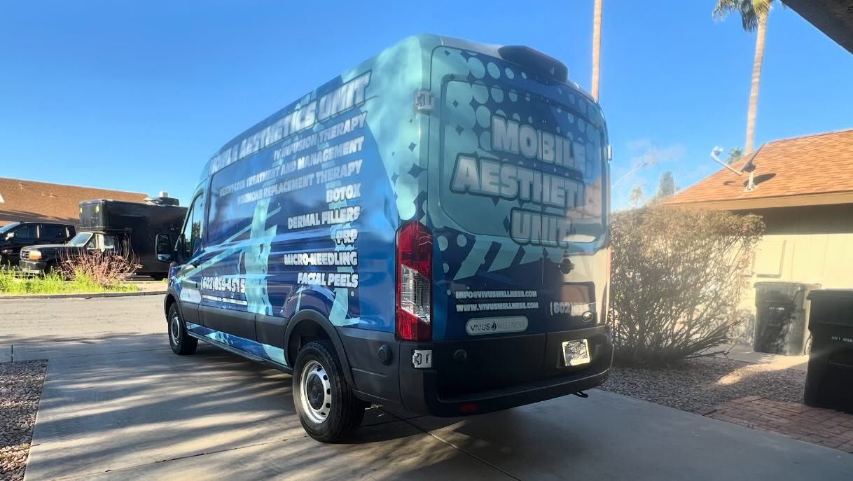 A blue and white van with mobile aesthetic clinic advertising parked in front of a house.
