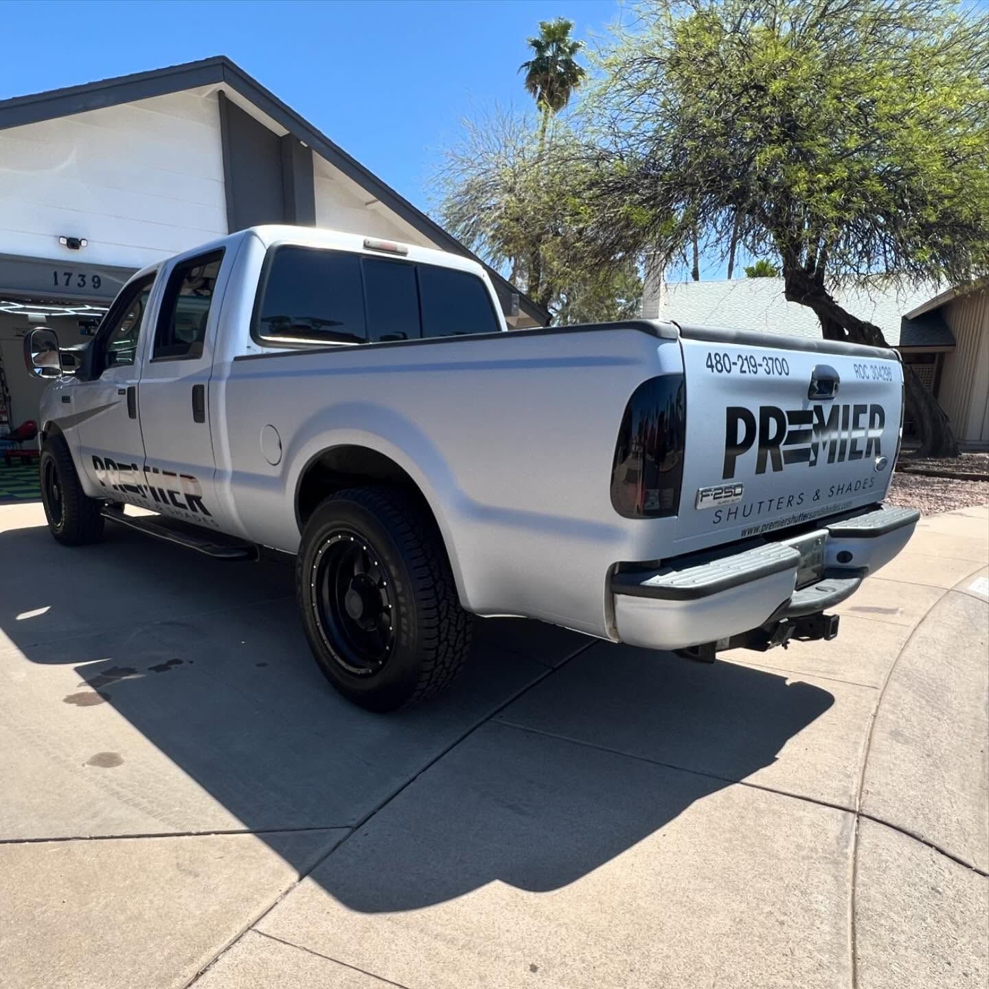 Silver pickup truck with black wheels and tinted taillights parked in a driveway.