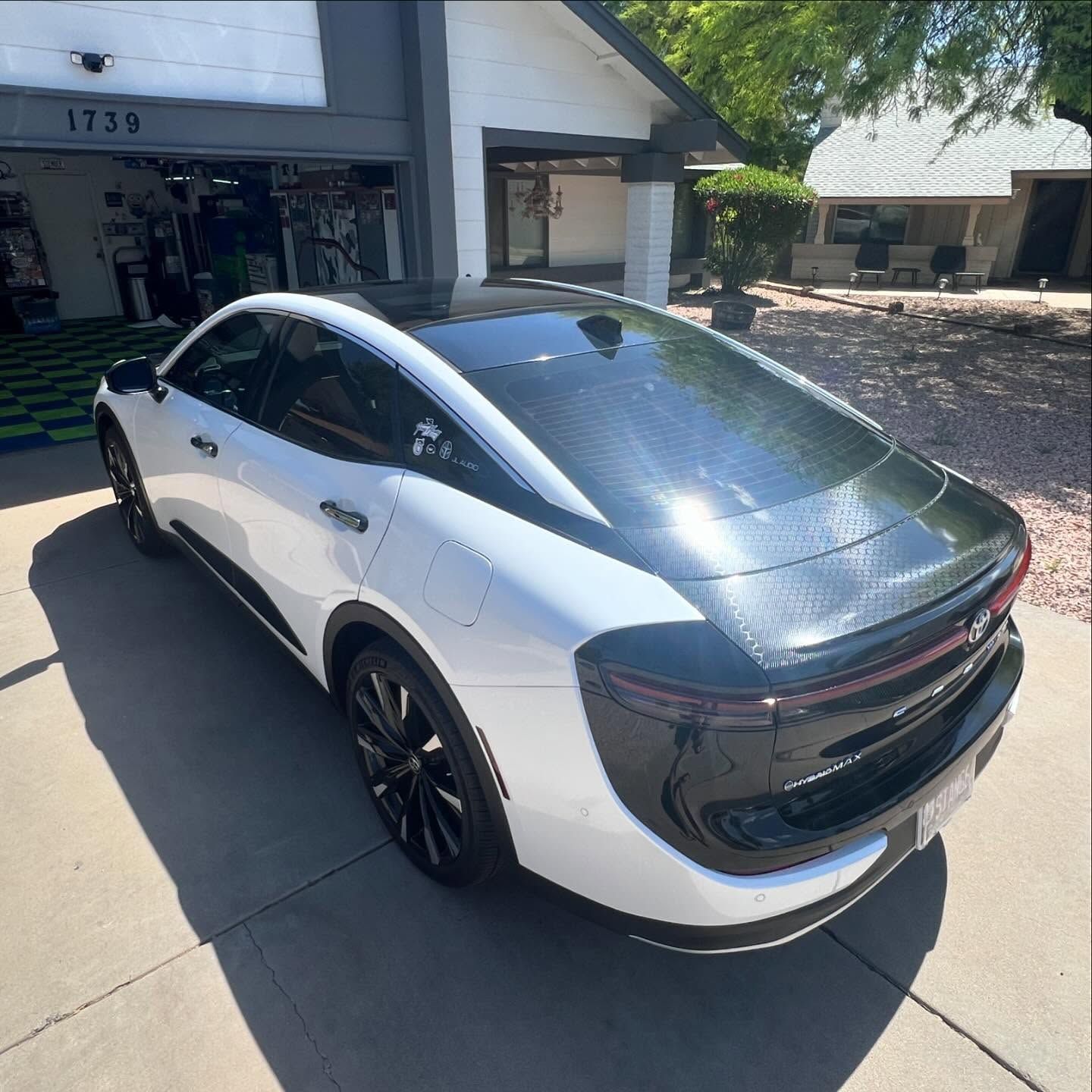 White and black electric vehicle parked in front of a building, with a dark roof.