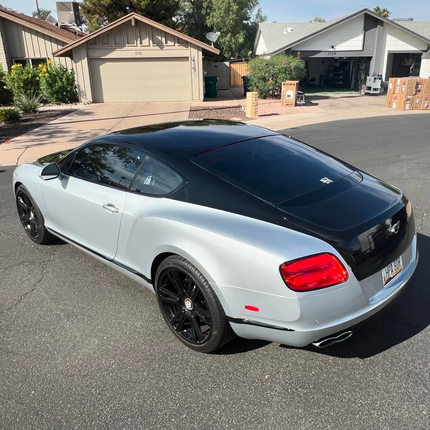 Silver and black Bentley coupe parked on a residential street.