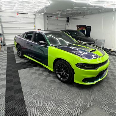 Lime green and dark purple Dodge Charger in a garage.