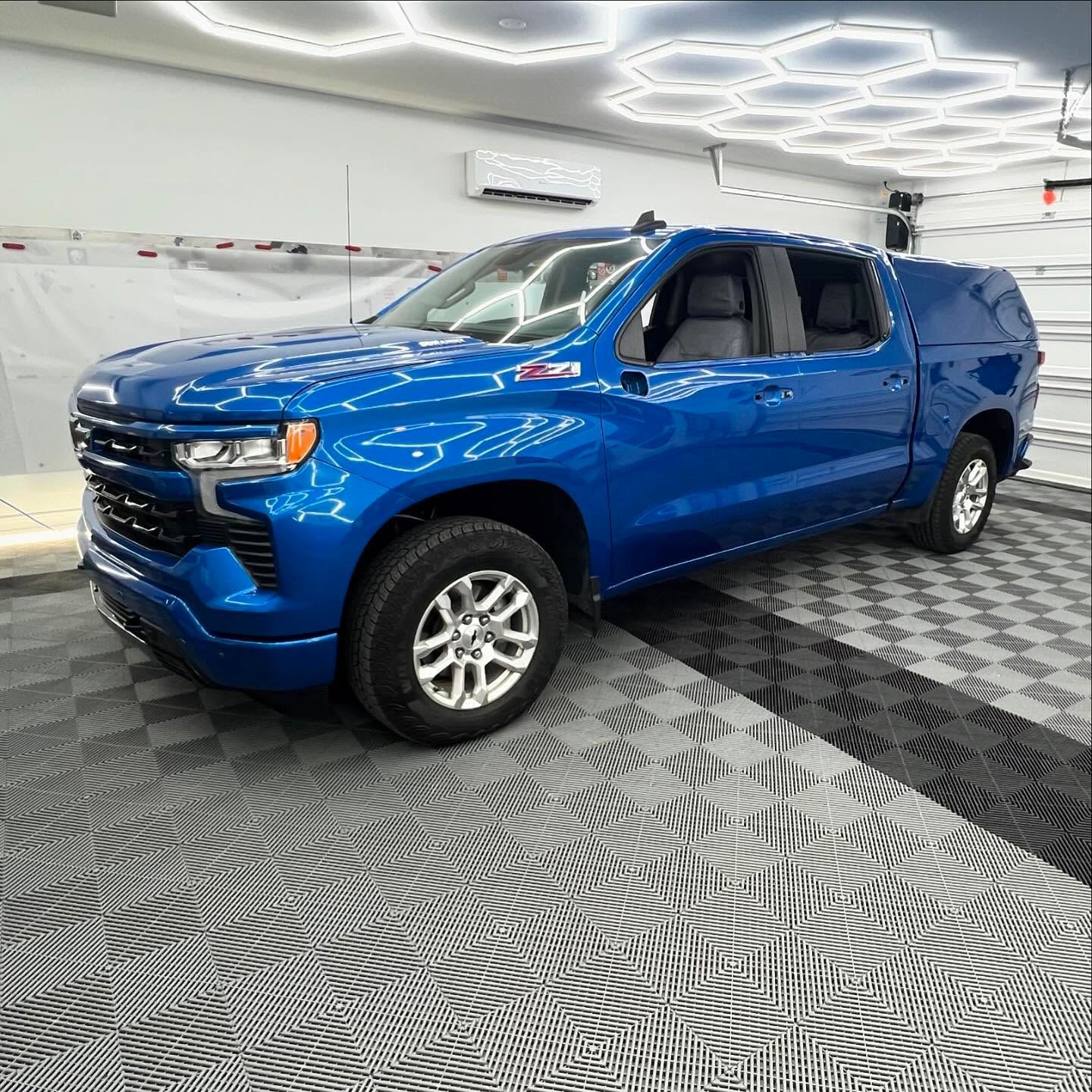 Blue Chevy Silverado pickup truck with a canopy, indoors.