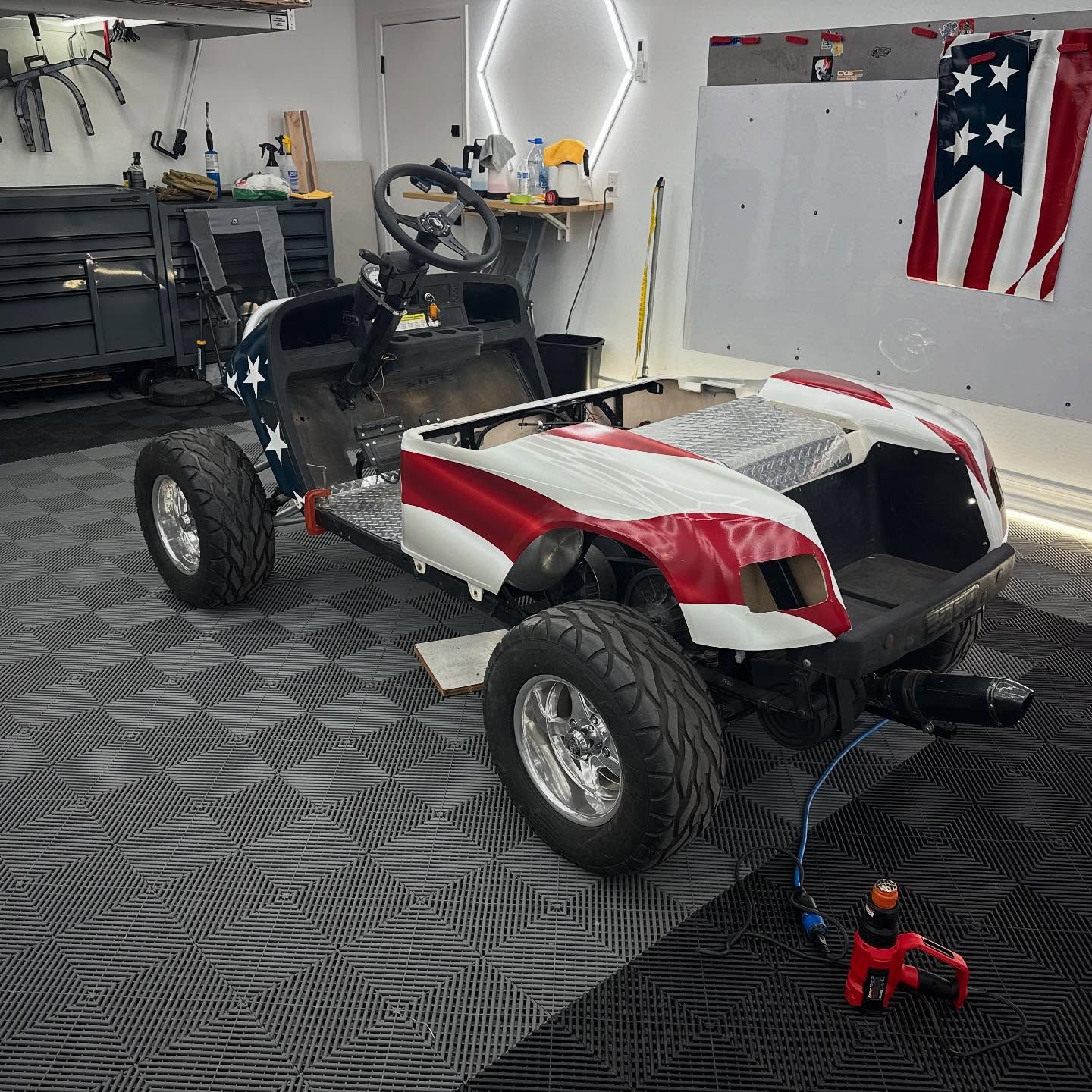 Golf cart customized with American flag paint job in a garage.