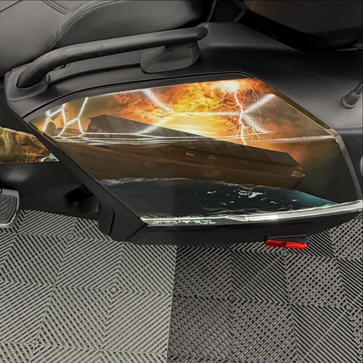 Motorcycle side panel with a dramatic landscape graphic of a stormy sky and rock formation.