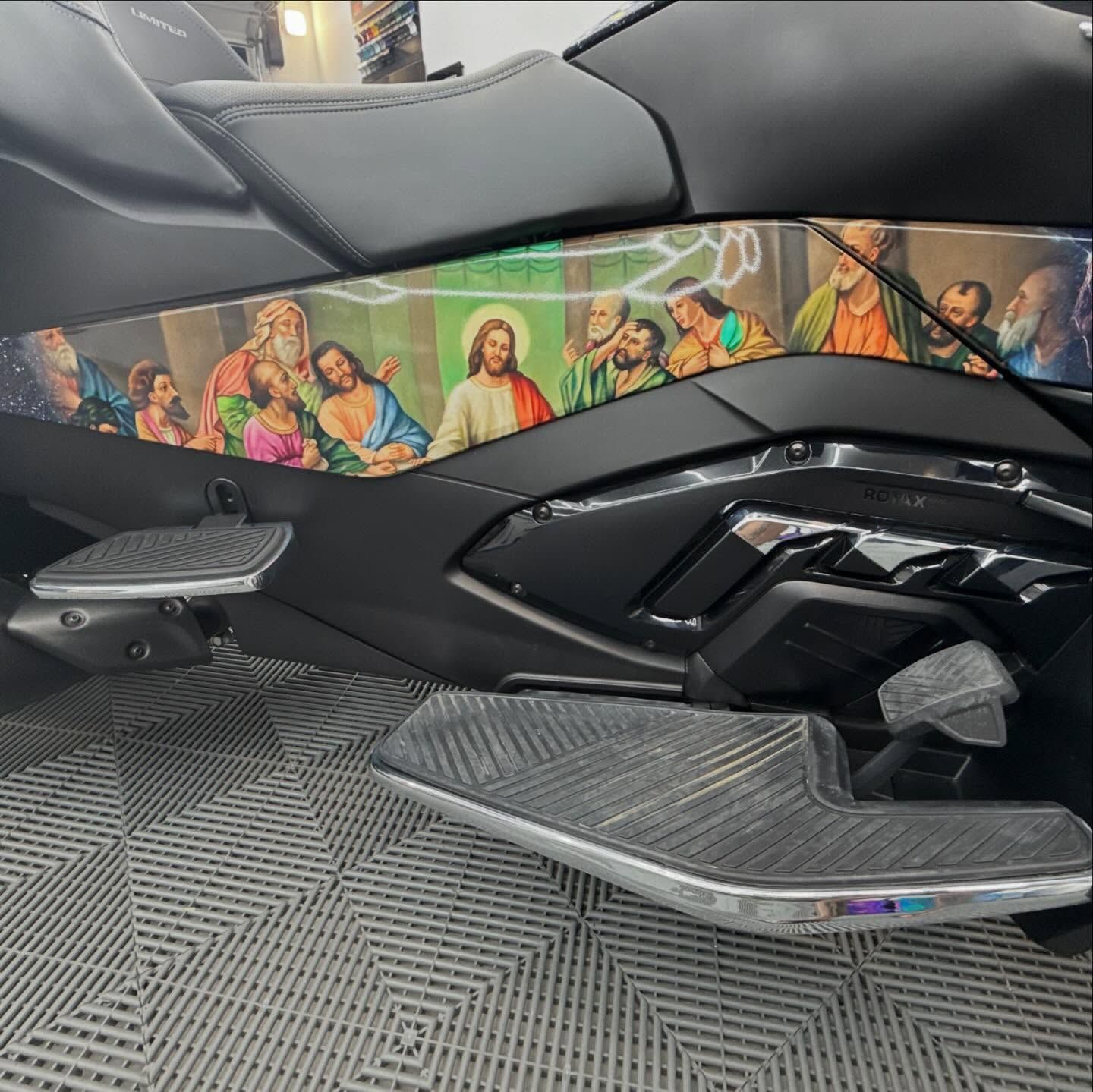 Black three-wheeled motorcycle with painted mural depicting Jesus and disciples. Silver footrests and glossy black panels.