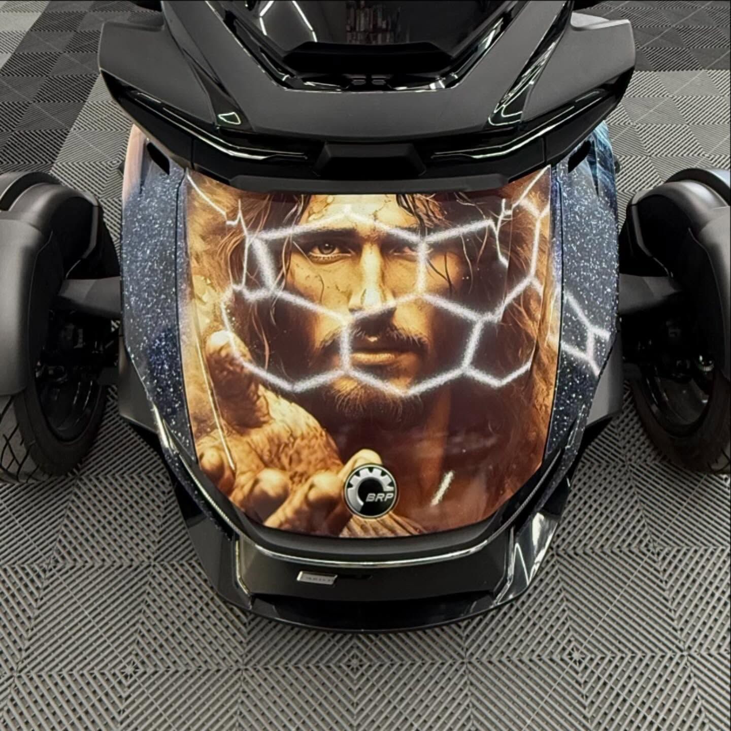 A black three-wheeled motorcycle with a Jesus graphic on the front