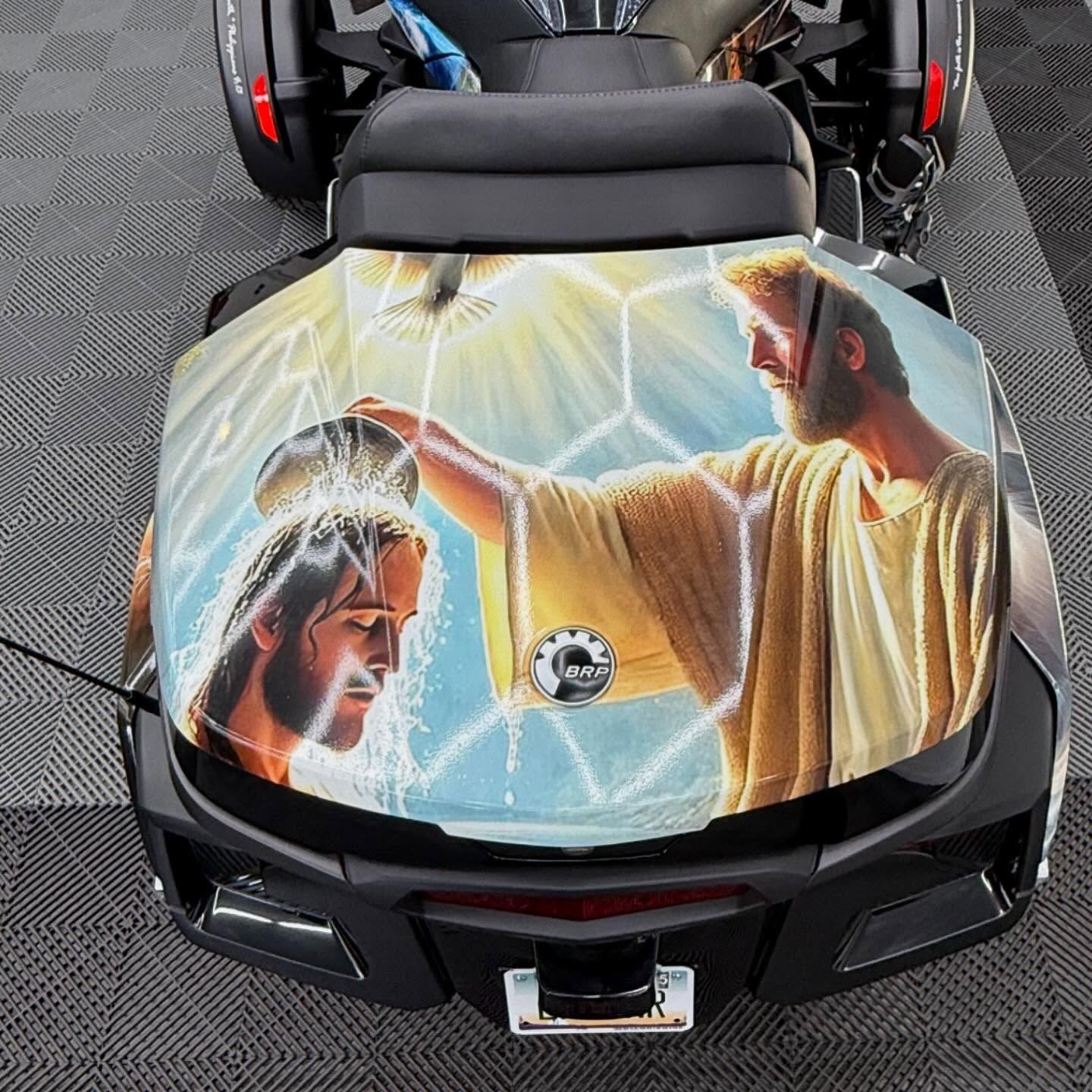 Motorcycle top case with Jesus baptizing another man, artistic depiction in blue and yellow.