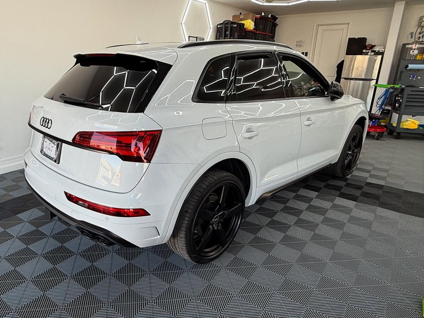 White Audi SUV with black wheels, parked indoors on patterned flooring.