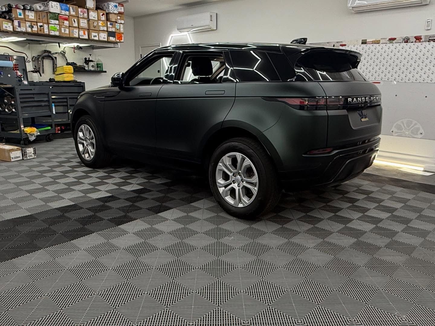 Dark matte black Range Rover Evoque in a garage with patterned flooring.