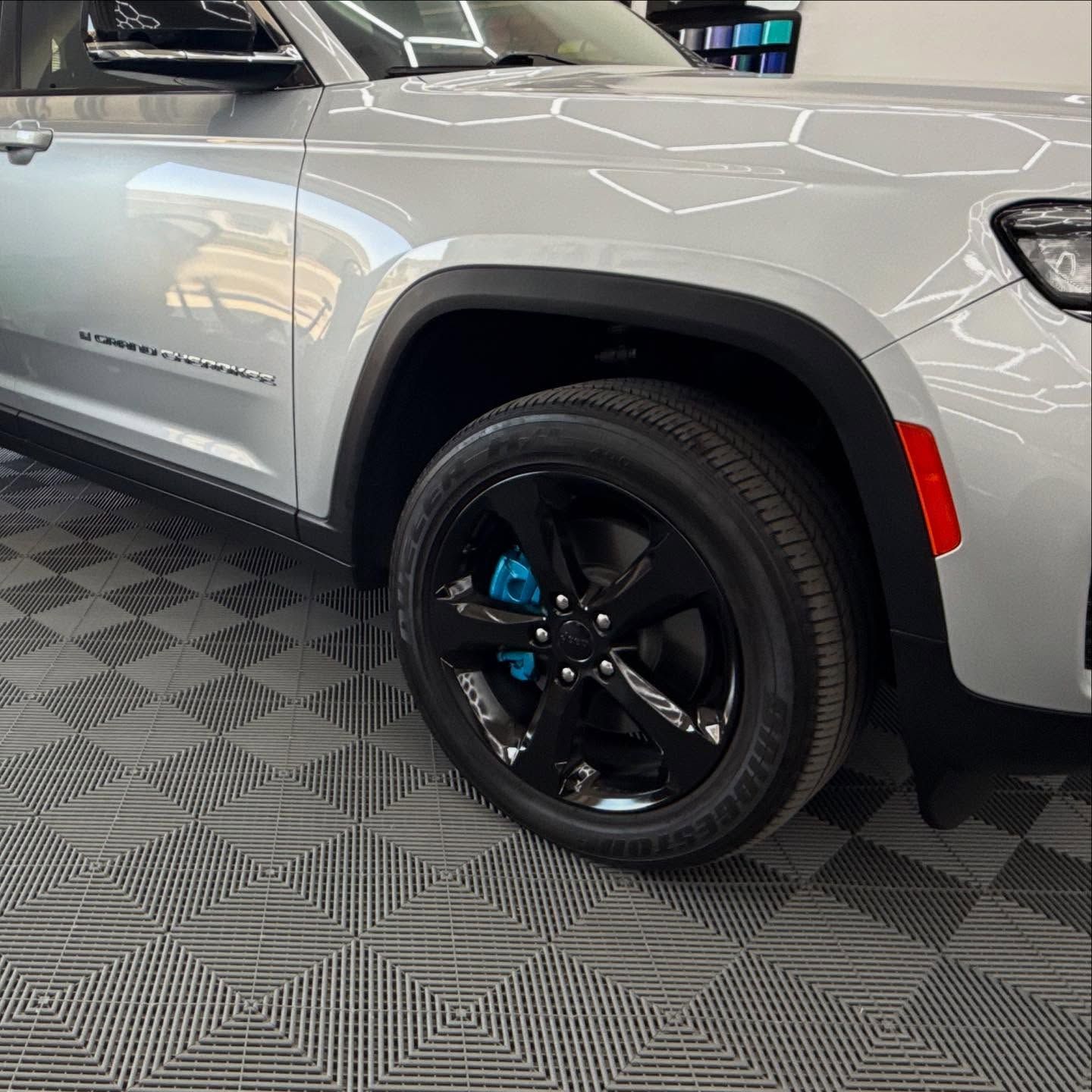 Silver SUV with black rims and blue brake calipers on a patterned floor.