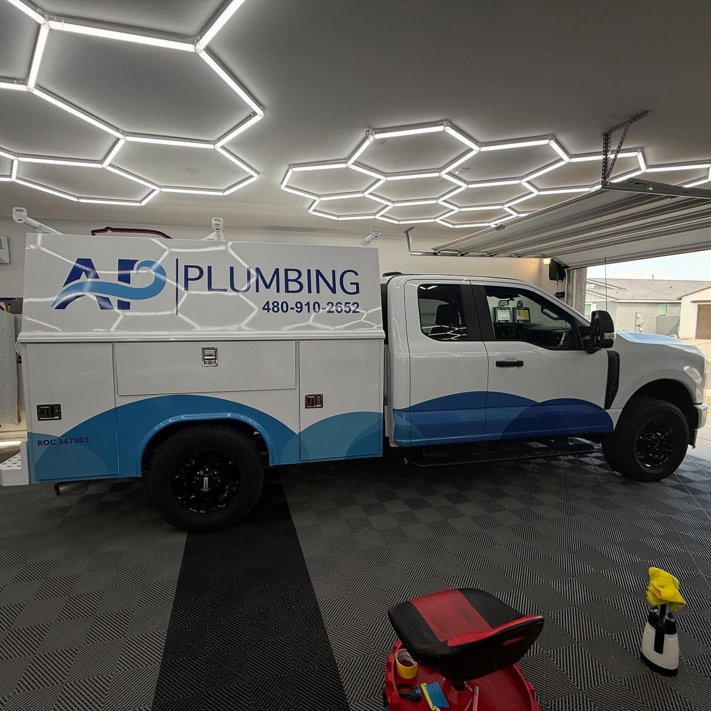 White plumbing truck with blue wave graphic, logo 