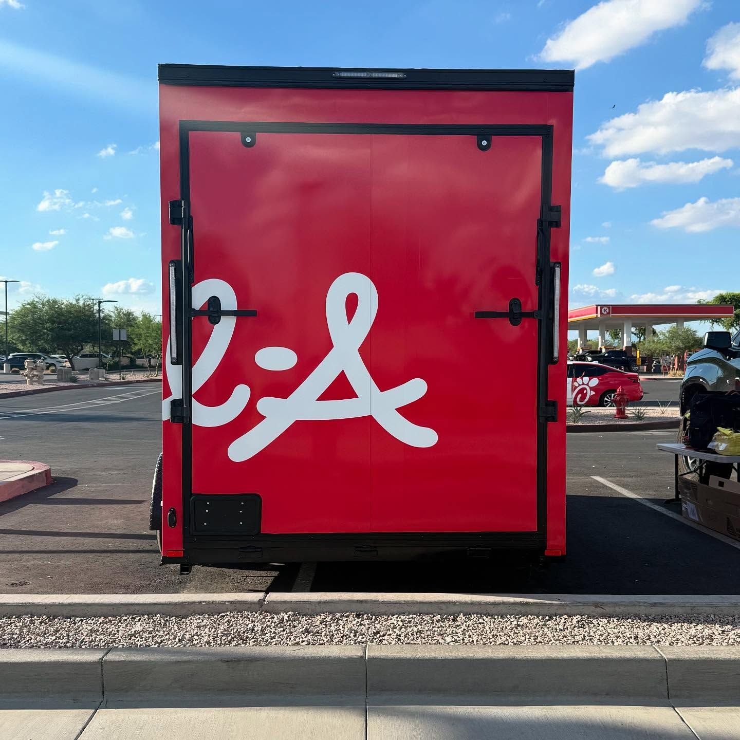 Red Chick-fil-A trailer with white logo parked outdoors in a parking lot.