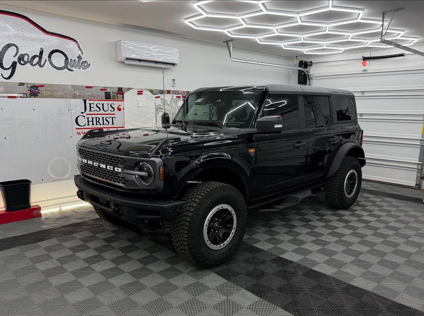 Black Ford Bronco parked in a brightly lit garage with a 