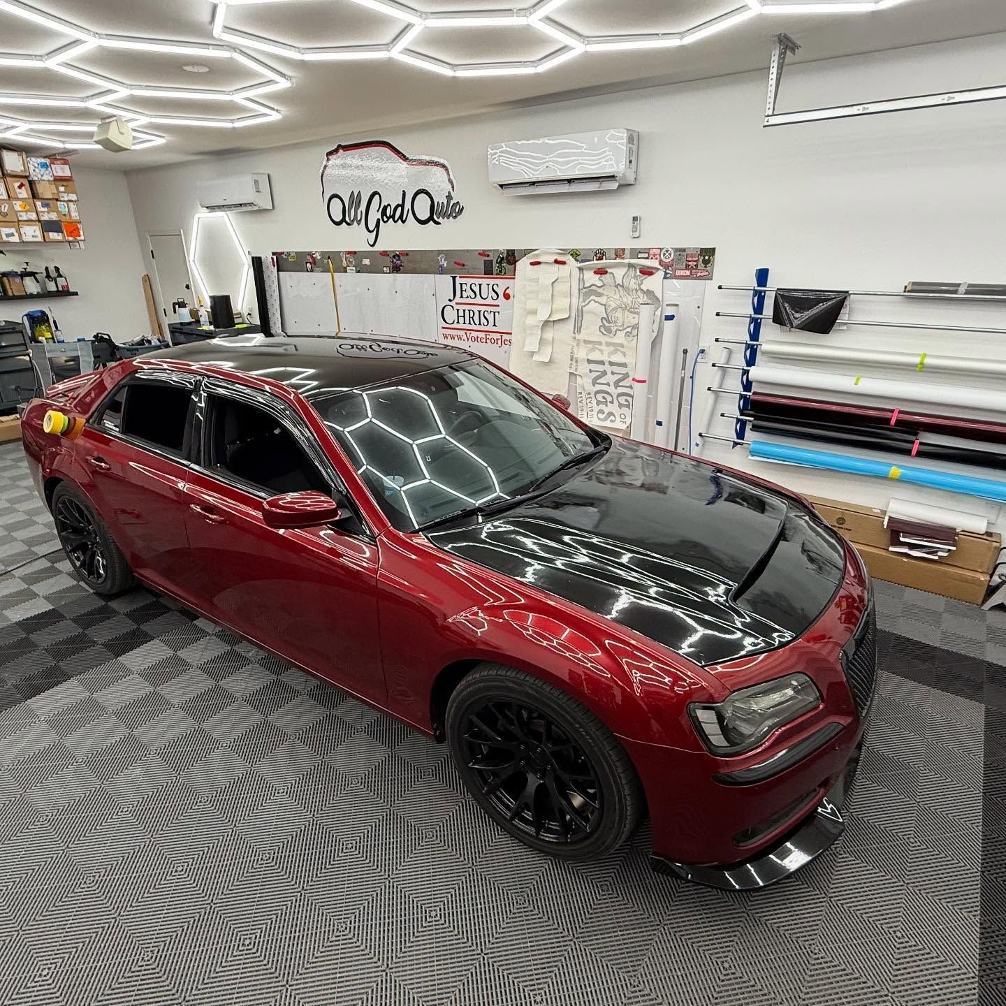 Red car with black hood inside a shop with hexagonal lights.
