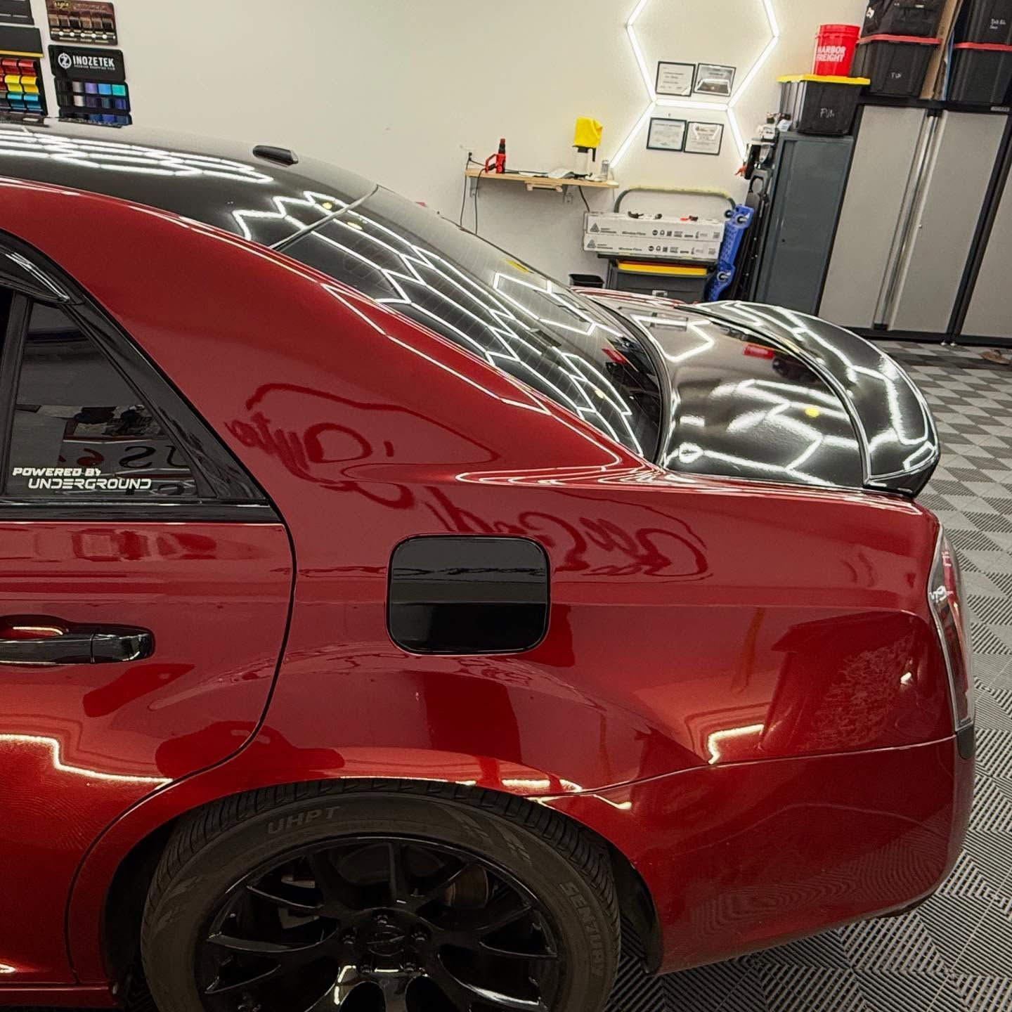 Red car with black wheels parked in a garage, shiny finish.