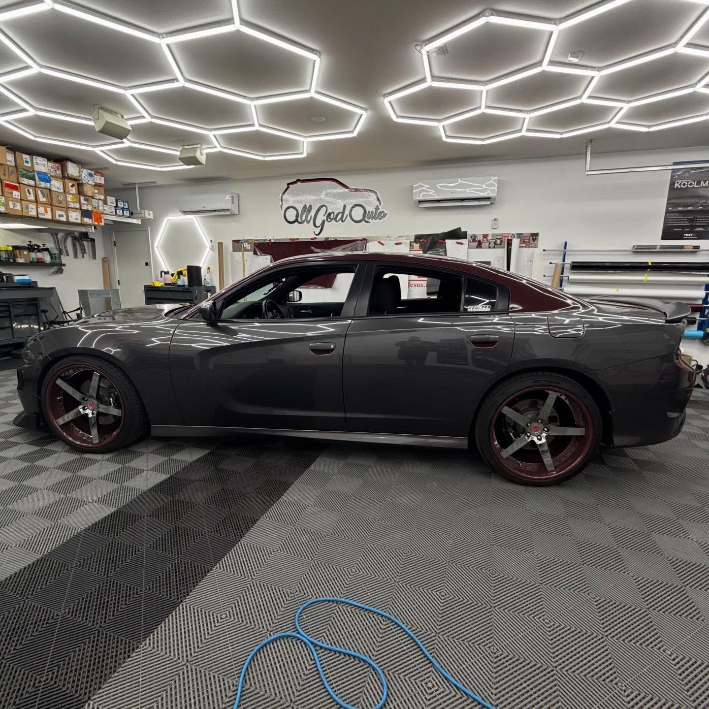 Dark gray Dodge Charger with maroon accents and rims inside a garage.