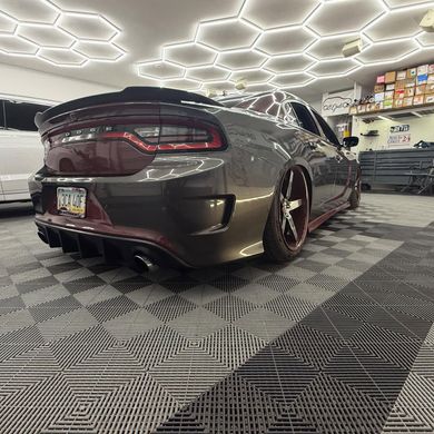 Gray and maroon Dodge Charger on tiled floor, low rider with red accents, under hexagon lights.