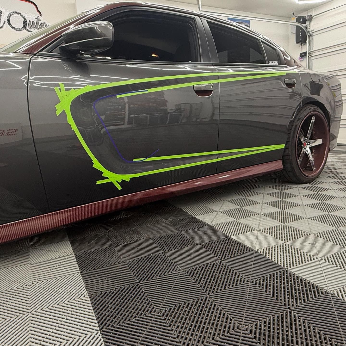 Gray car with green accent lines and a burgundy trim, parked on a patterned floor.