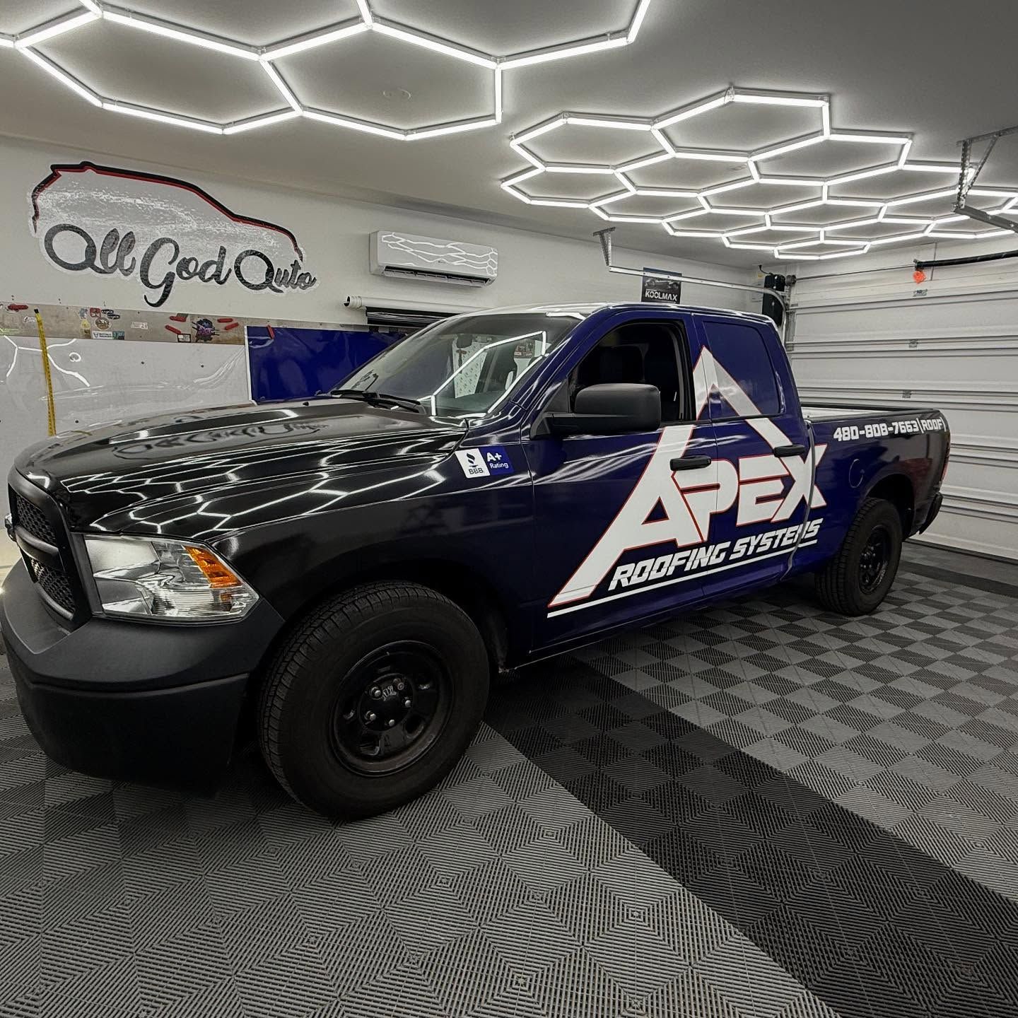 Black and blue Apex Roofing Dodge Ram truck parked inside a garage.