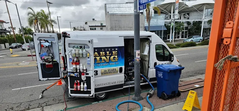 A person is cleaning a couch with a steam cleaner.
