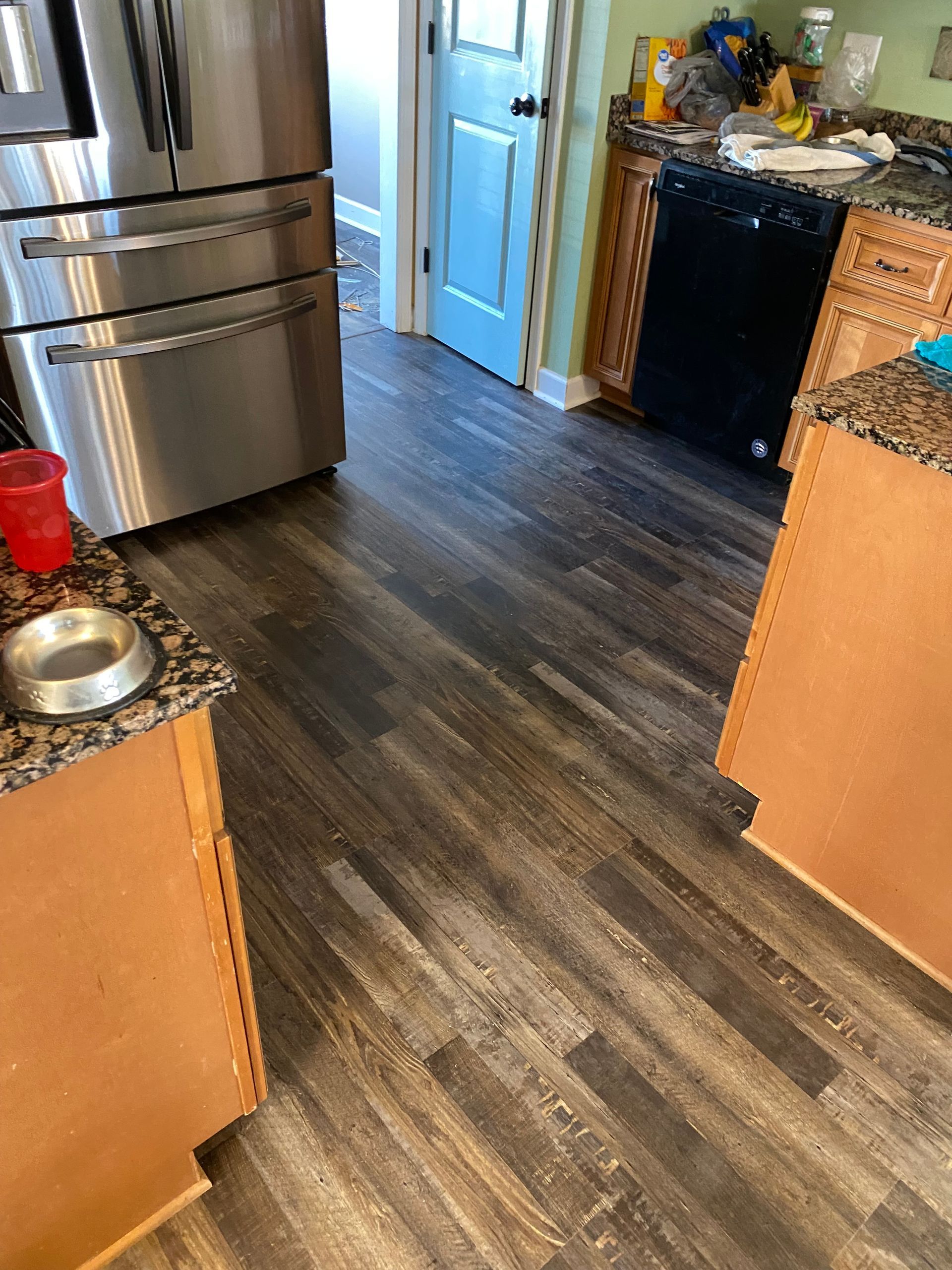 A kitchen with a stainless steel refrigerator and a dog bowl on the counter.