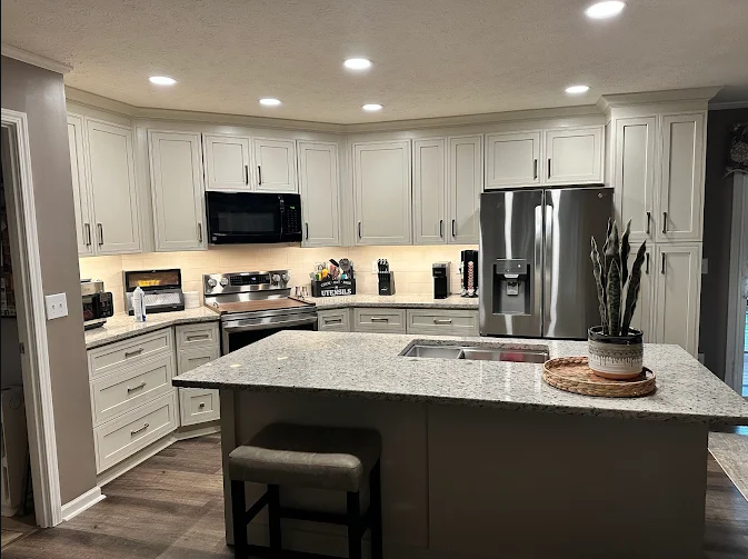 A kitchen with white cabinets , granite counter tops , stainless steel appliances and a large island.