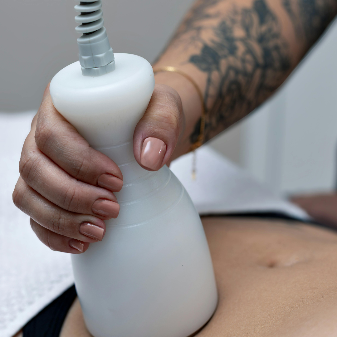 Hand holding a white handheld device on a person's bare abdomen during a treatment