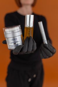 A professional wearing pink gloves uses a small syringe to administer a cosmetic injection near a smiling person's eye.