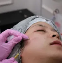 A practitioner uses an ultrasound therapy device with gel on a patient's back during a clinical treatment.