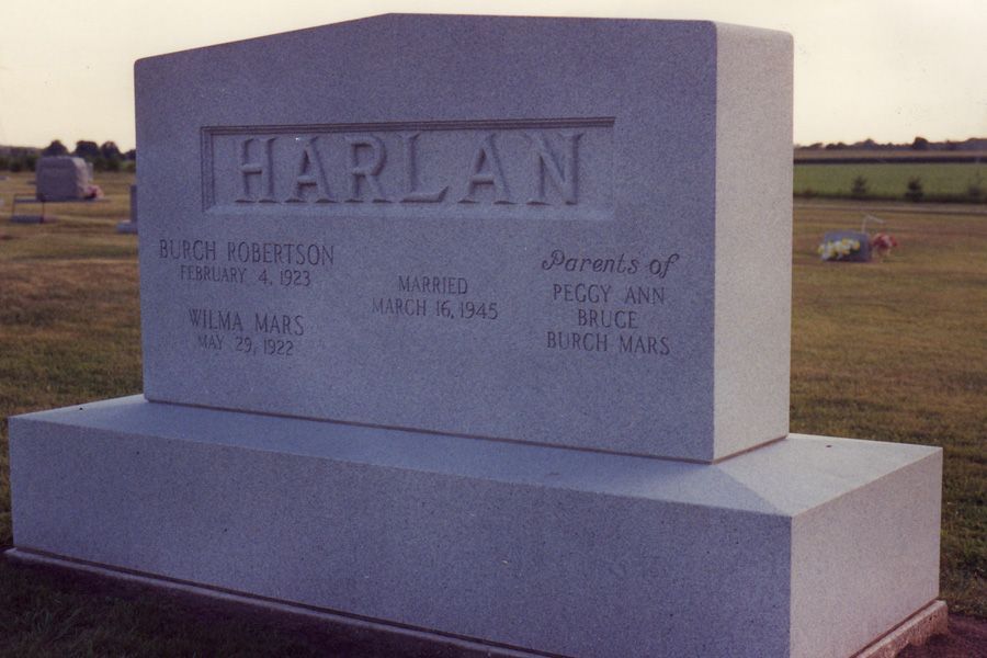 A gravestone for harlan sits in a grassy field