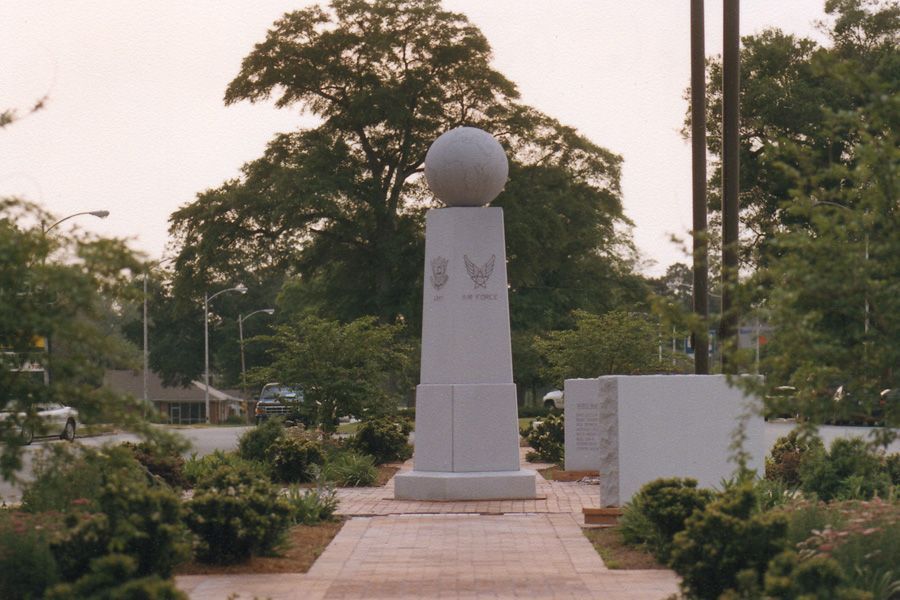 A statue in a park with a globe on top of it
