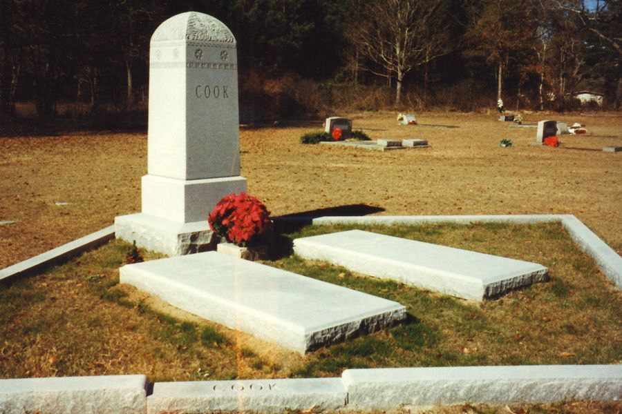 A cemetery with three graves and a monument that says cook