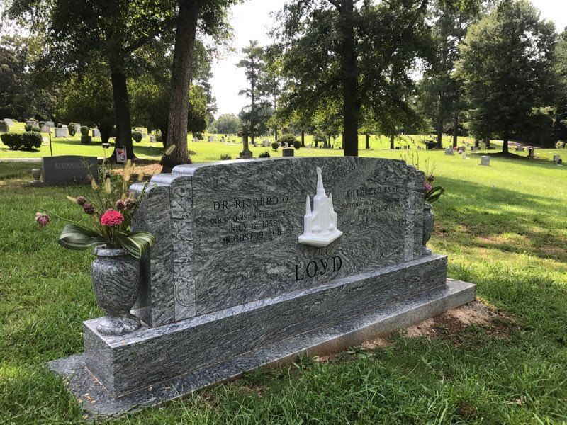 A grave in a cemetery with a vase of flowers on it.