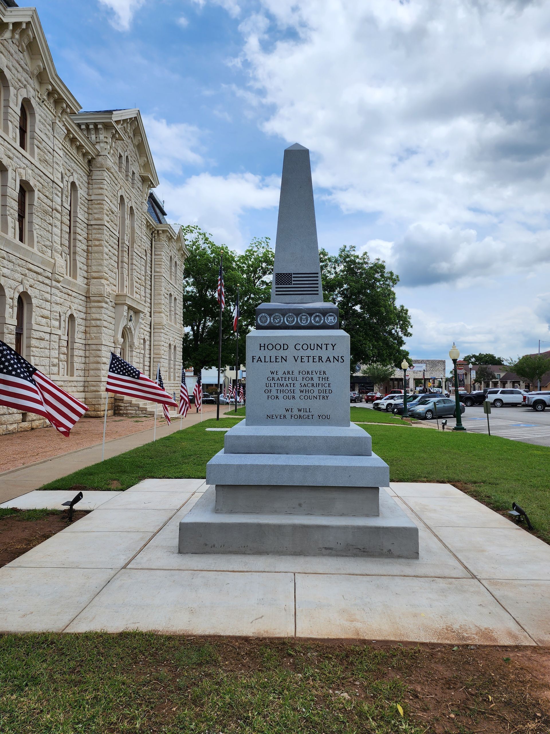 A monument in front of a stone building with american flags in the background.