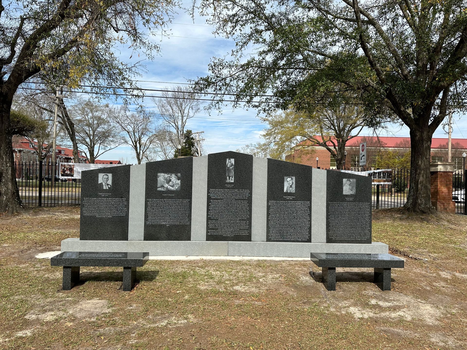 A memorial in a park with two benches in front of it.