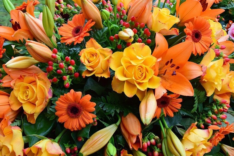 Bouquet of orange and yellow flowers, including lilies, roses, and gerbera daisies.