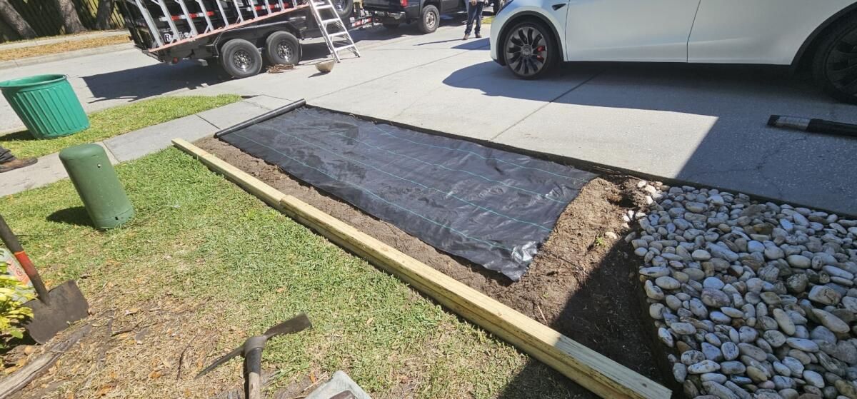 A white car is parked in a driveway next to a pile of dirt and rocks.