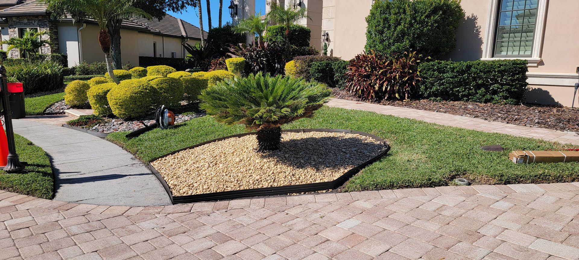 A brick driveway leading to a house with a lush green lawn.