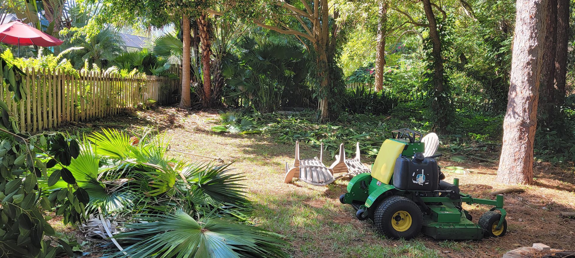 A green lawn mower is parked in the middle of a lush green yard.
