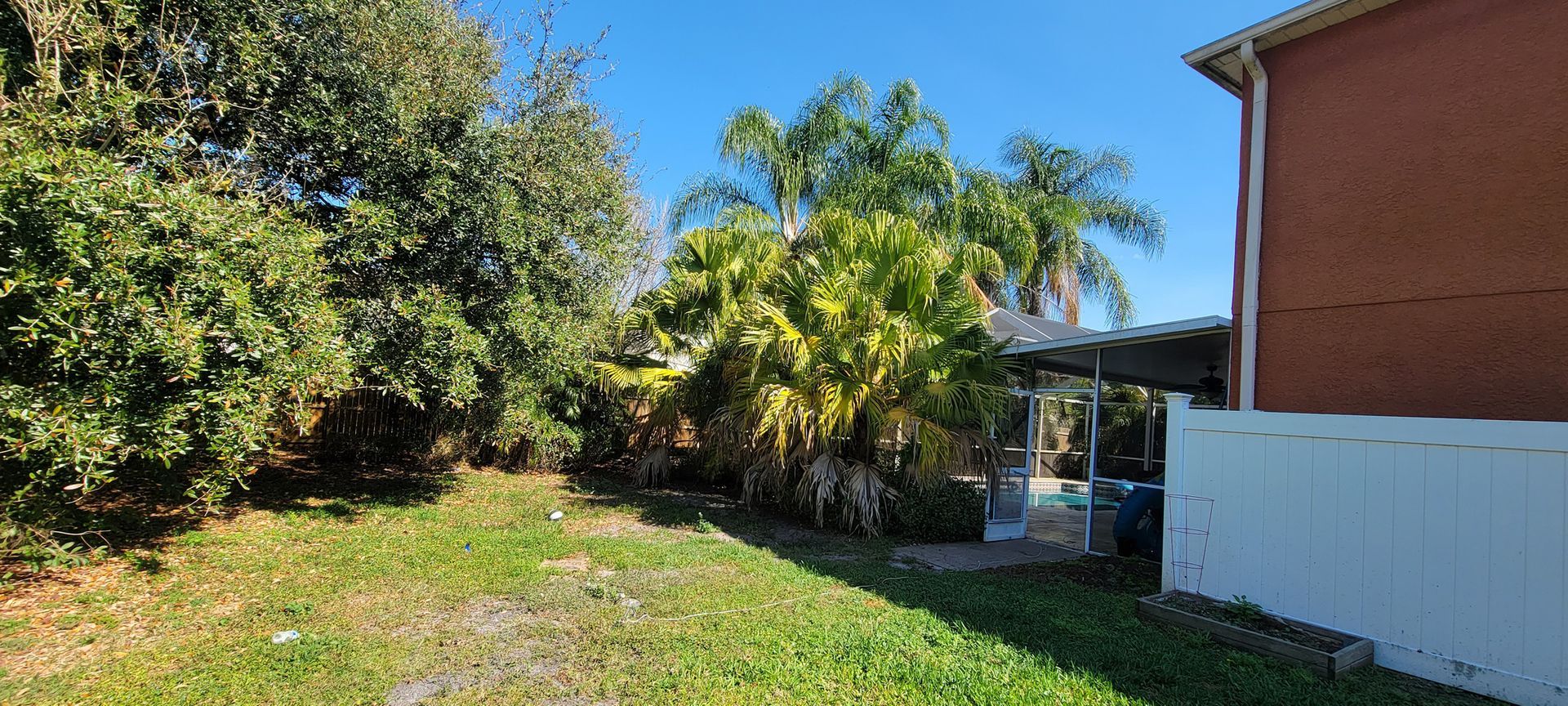 A brick house with a white fence and trees in front of it.