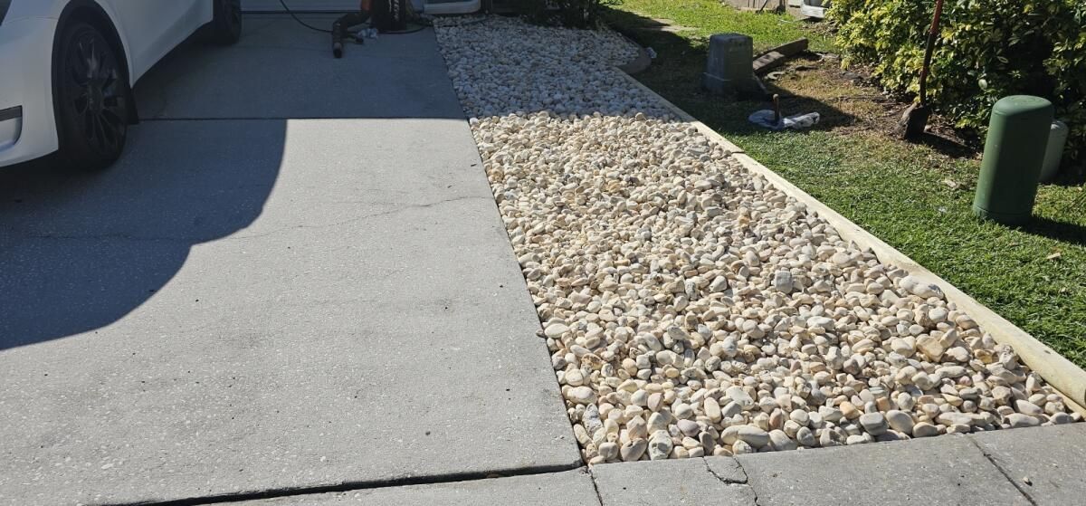 A white car is parked in a driveway next to a gravel path.