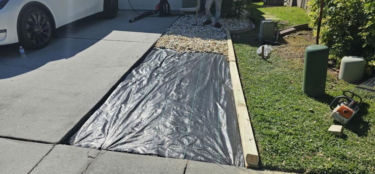 A car is parked in a driveway next to a sidewalk covered in plastic.