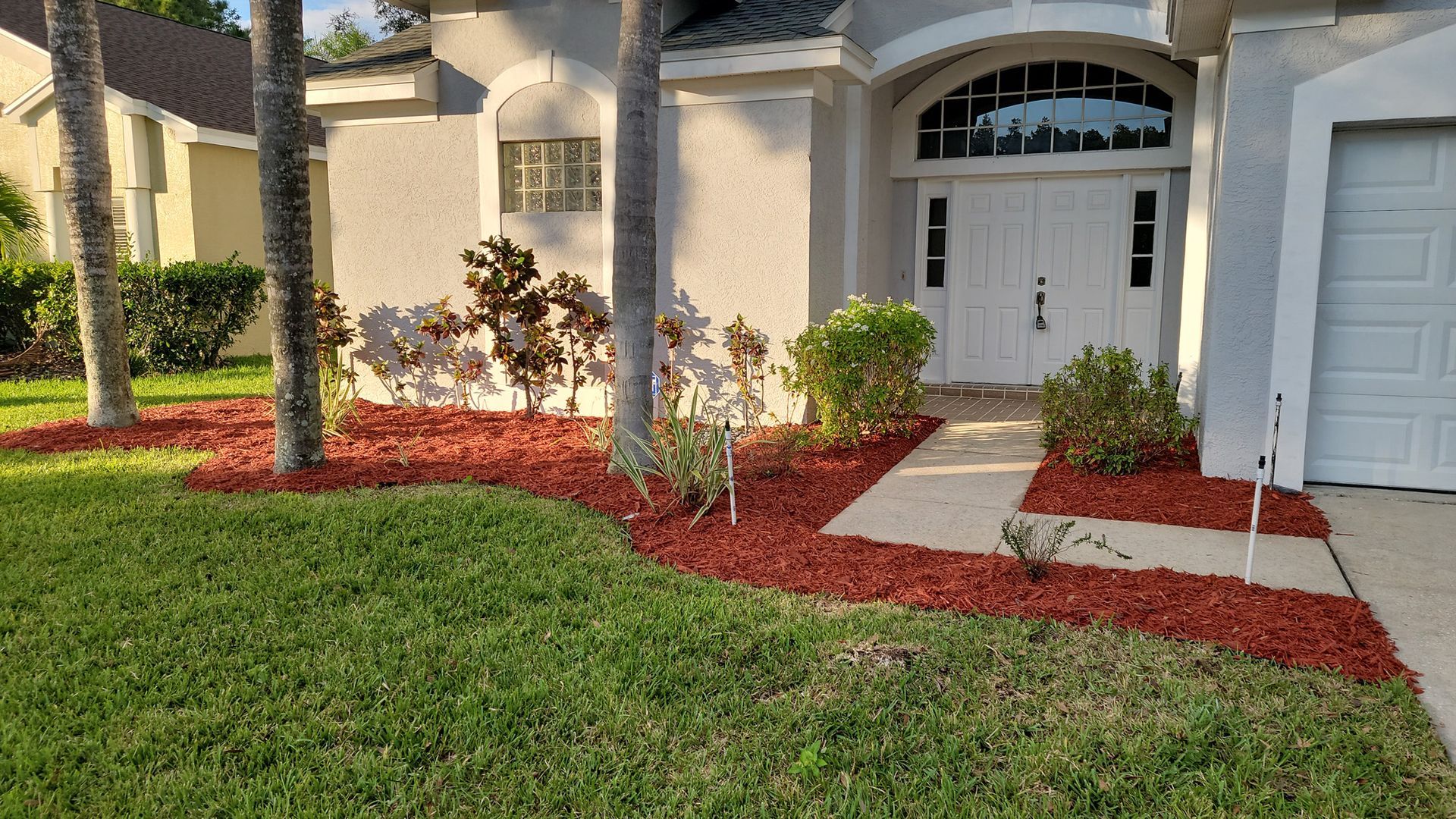 The front of a house with a lush green lawn and a white garage door.