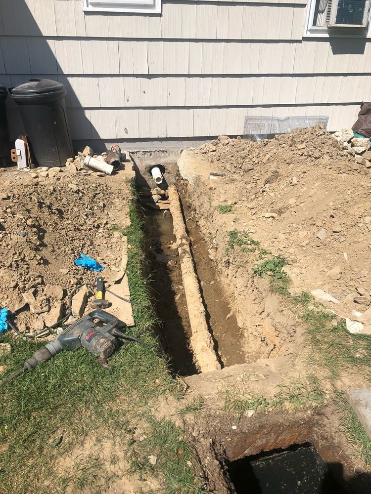 A drain pipe is being installed in the backyard of a house.