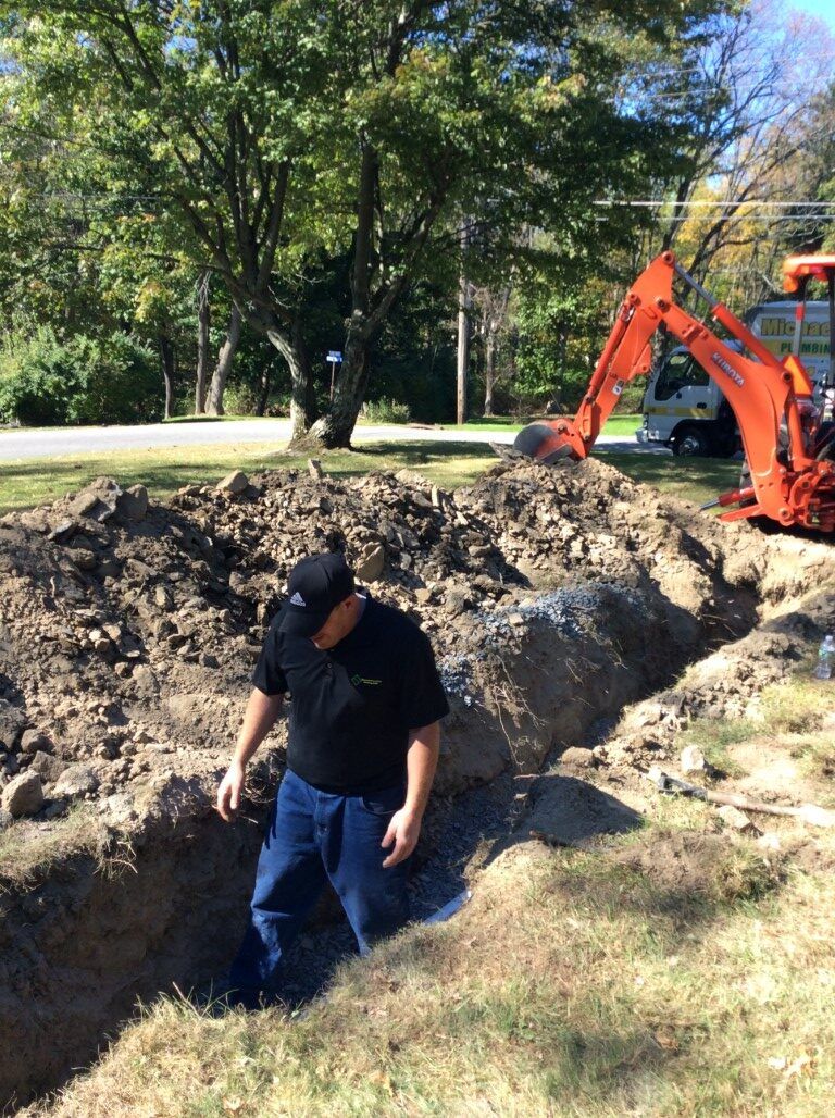 A man is standing in a hole in the ground next to a bulldozer.