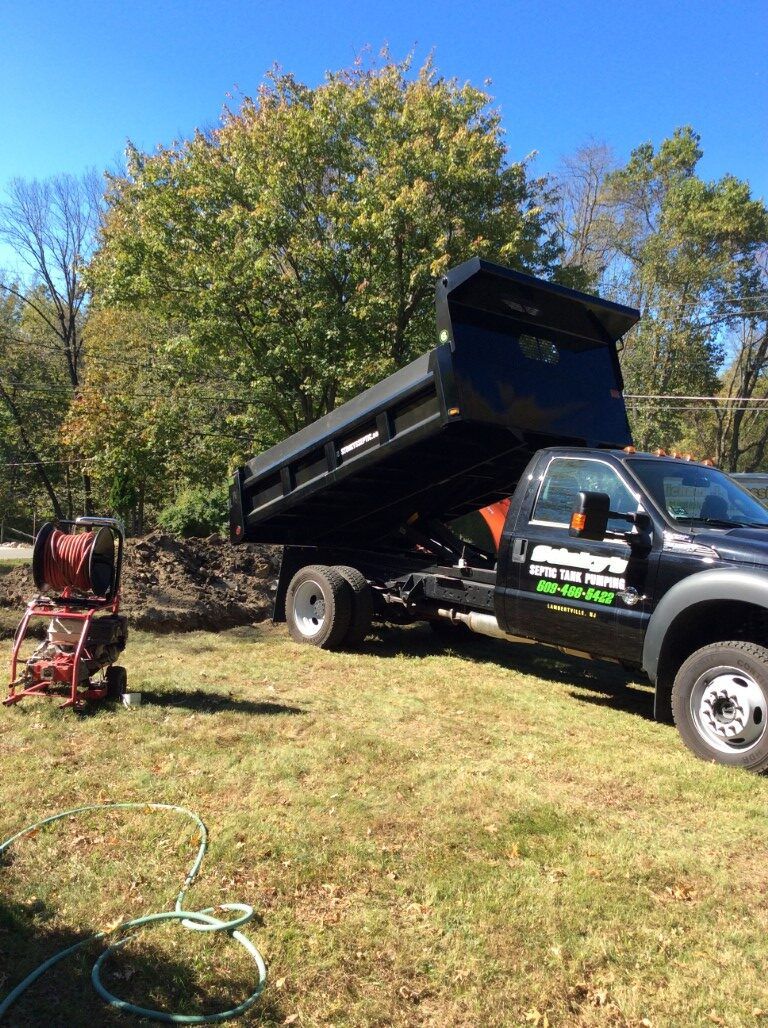 A dump truck is parked in a grassy field.
