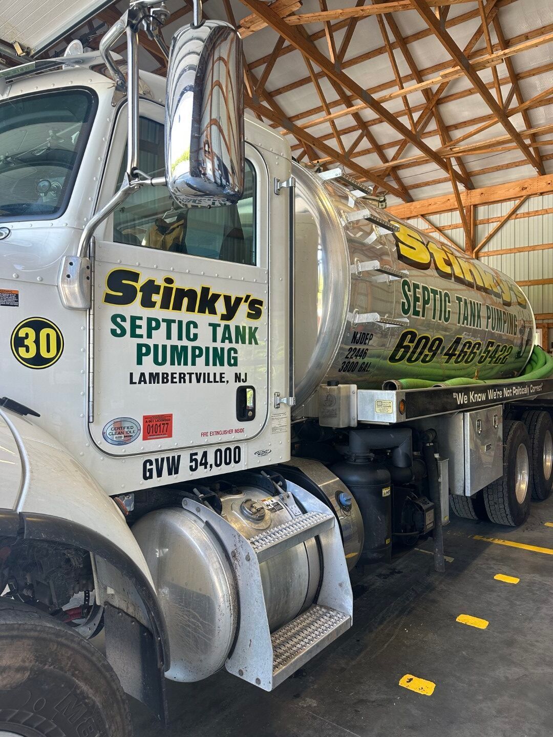 A septic tank pumping truck is parked in a barn.