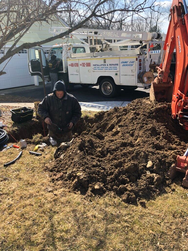 A man is digging a hole in the ground in front of a truck.